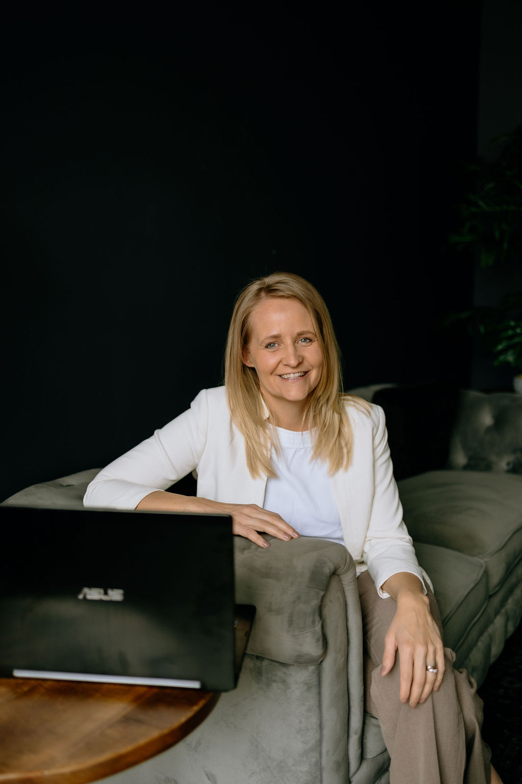 Toni Schafer seated on a couch with a laptop, working — professional educator and speaker