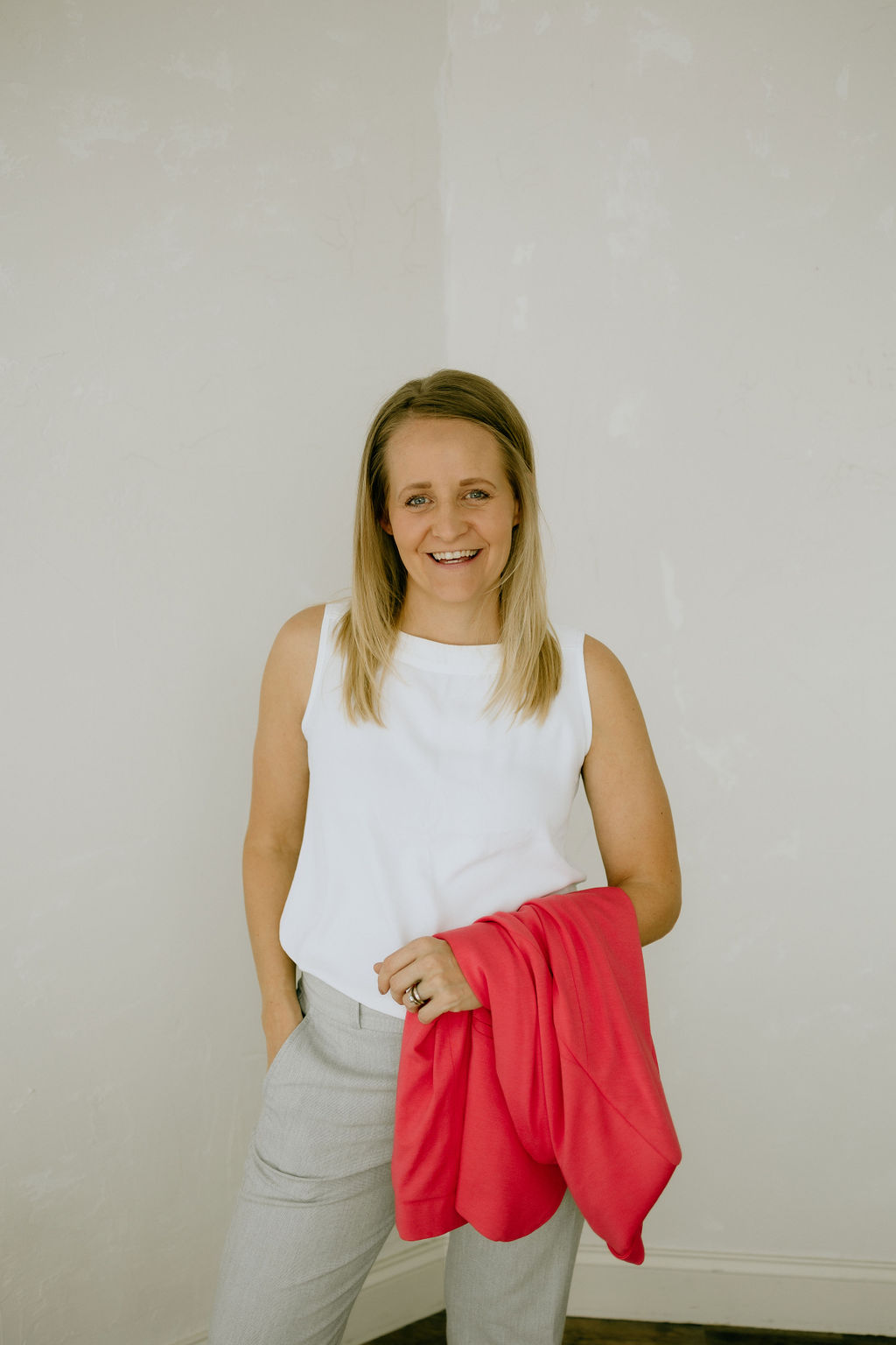Toni Schafer standing and smiling, holding a coral blazer — ready to connect
